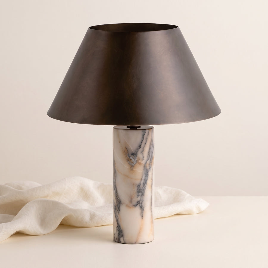 Cline Vesper marble and metal table lamp beside draped linen