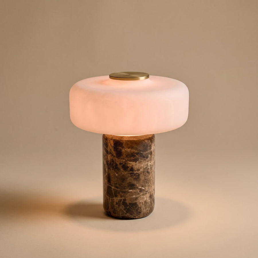 Lysa marble and glass table lamp, lit, on a warm beige background