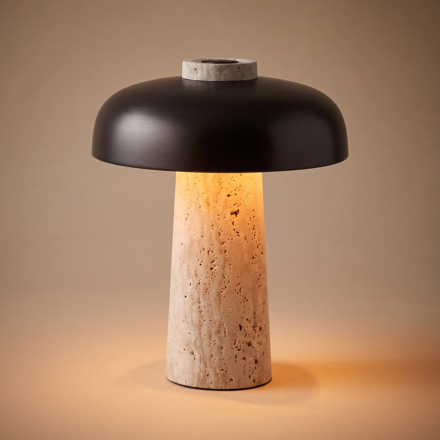 Silex rechargeable travertine table lamp, lit, on a warm sand beige studio backdrop