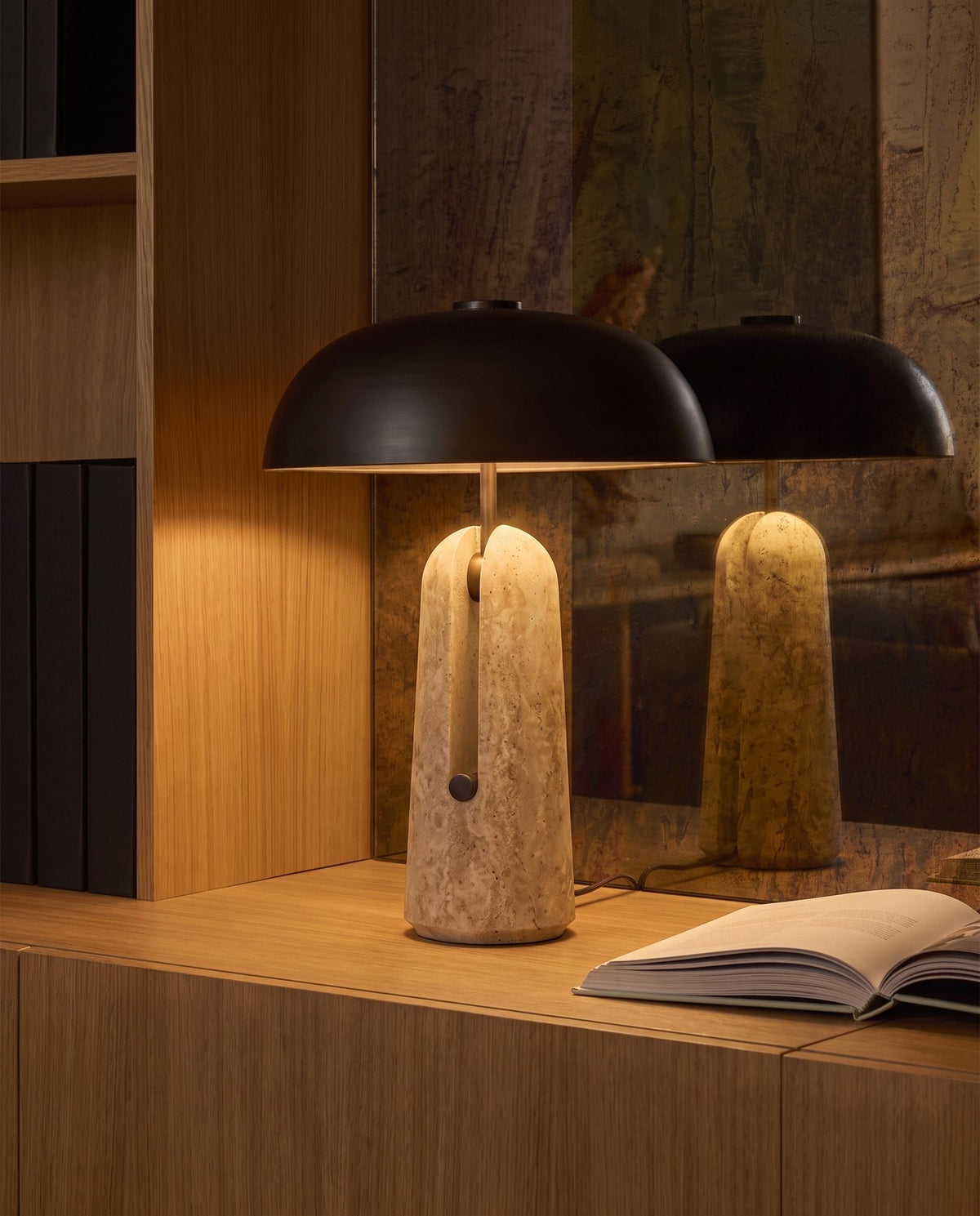 Sillon travertine and iron table lamp, lit, on an oak built-in cabinet before an antique mirror