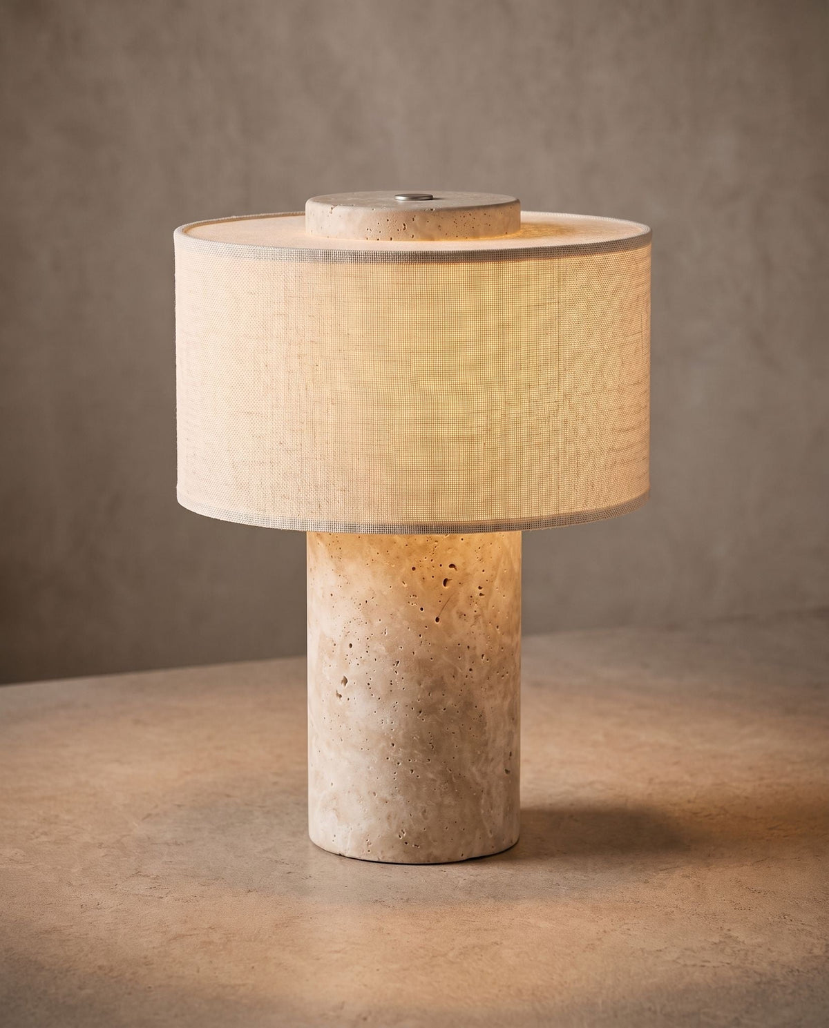 Auren rechargeable stone table lamp, lit, on a pale stone tabletop against a textured plaster wall