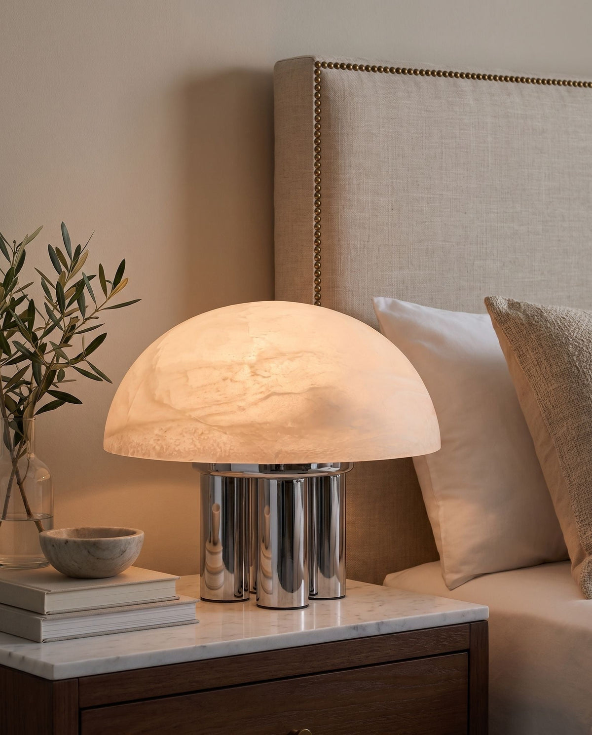 Iris dome table lamp, lit, on a marble-top nightstand by the bed