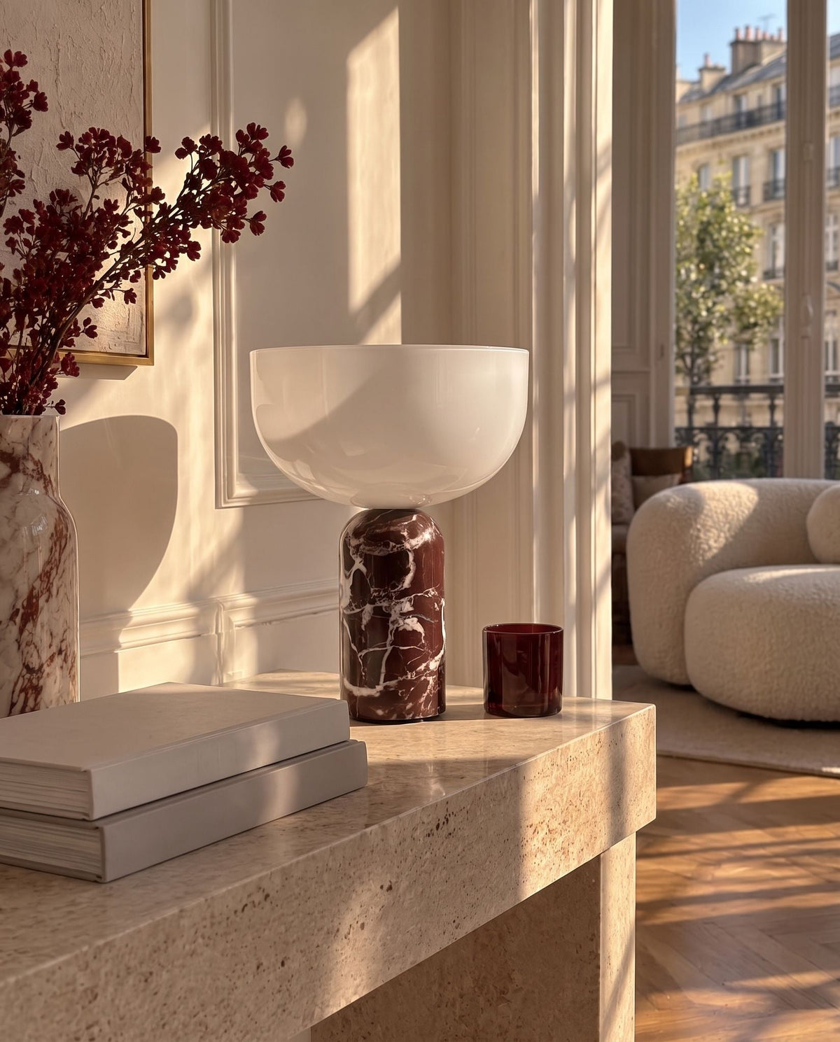 New Works marble and glass table lamp on a travertine console in a sunlit living room