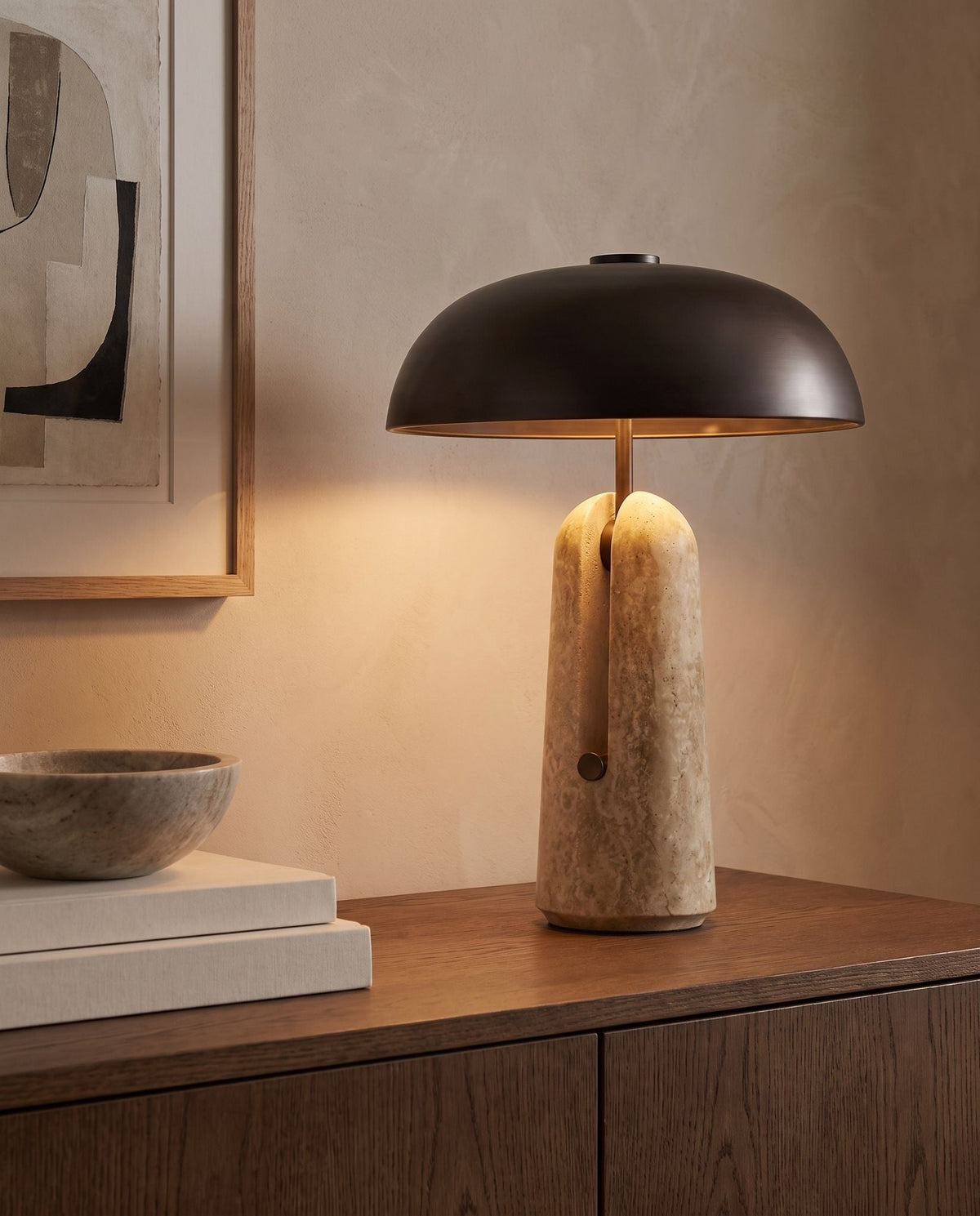 Sillon travertine and iron table lamp, lit, on a walnut sideboard, abstract art behind