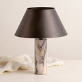 Cline Vesper marble and metal table lamp beside draped linen