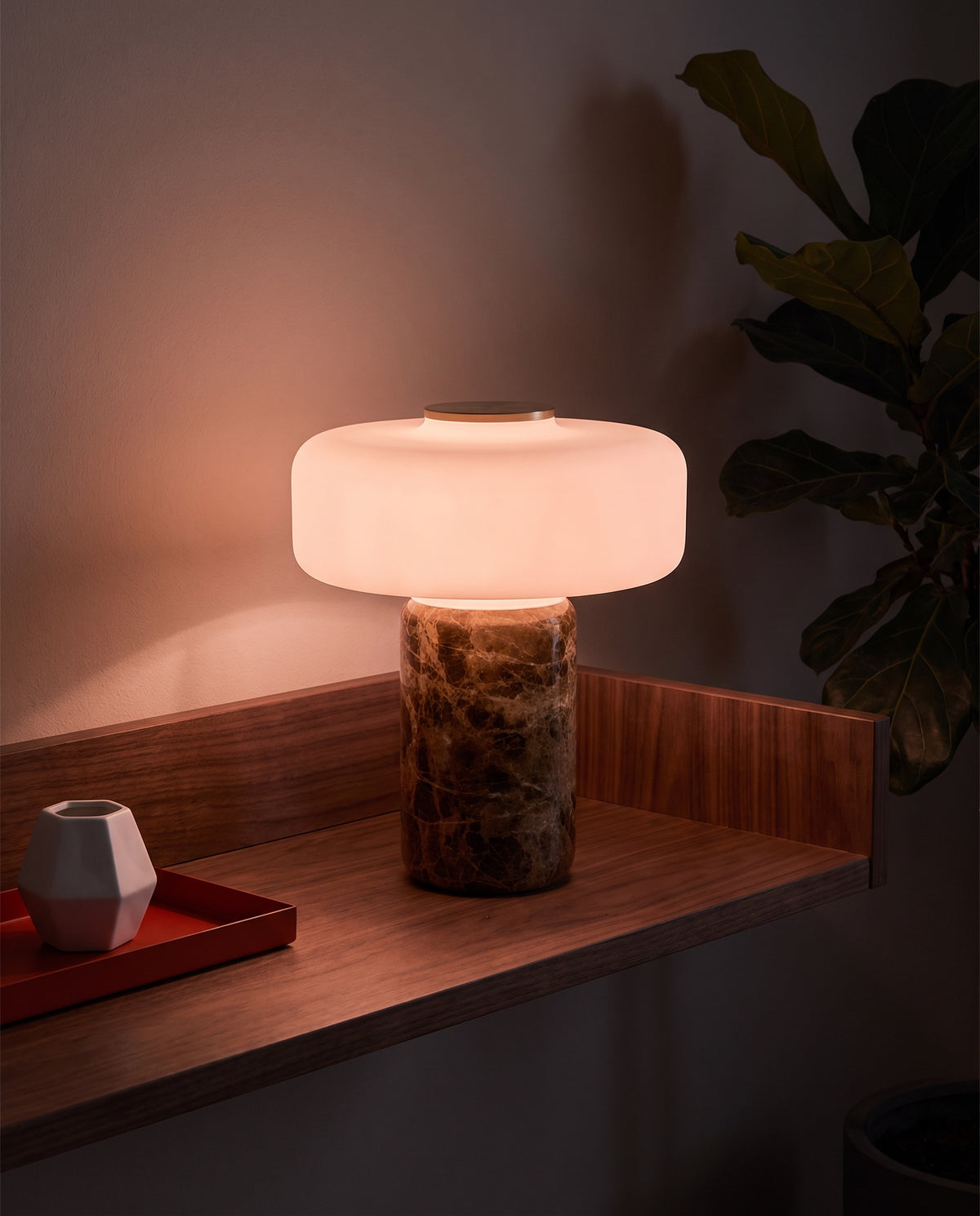 Lysa marble and glass table lamp, lit, on a walnut wall shelf at night