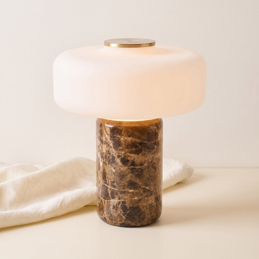 Lysa marble and glass table lamp, lit, beside draped linen