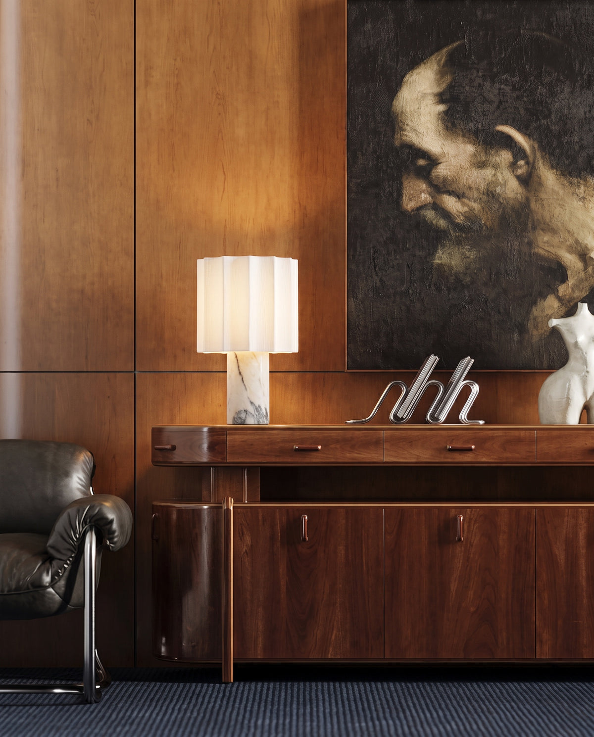 Macara marble and fabric table lamp, lit, on a walnut sideboard in a wood-paneled room with a portrait