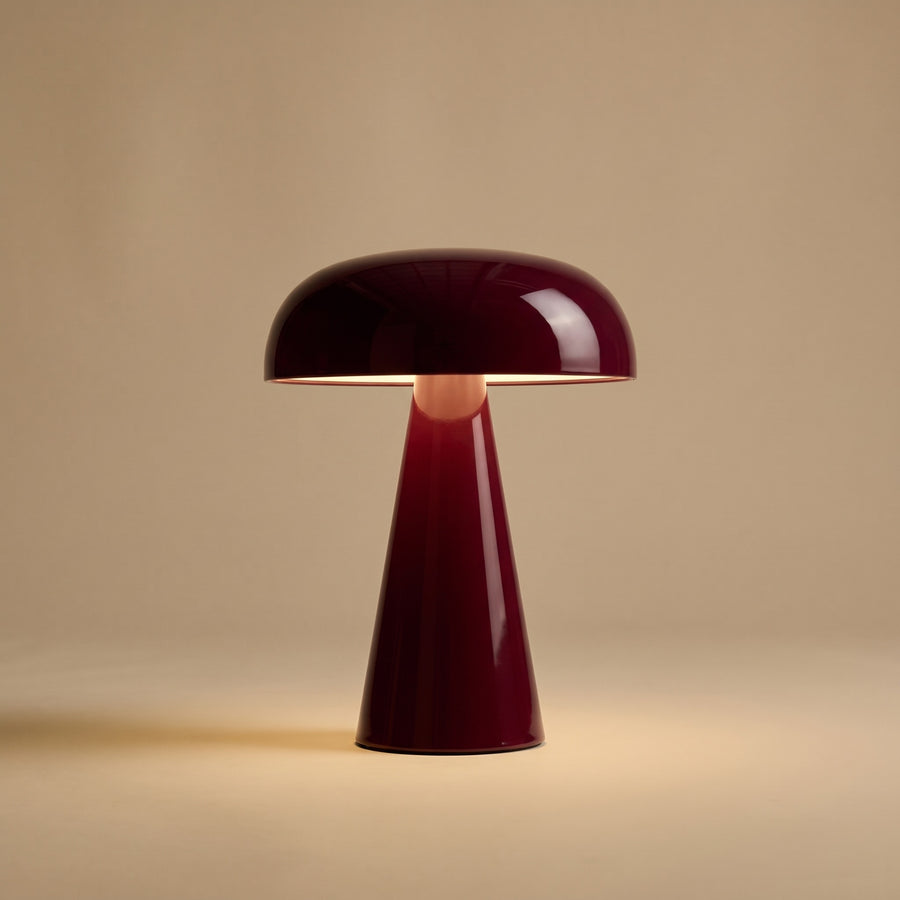 Rubra lacquered table lamp, lit, on a warm sand studio backdrop