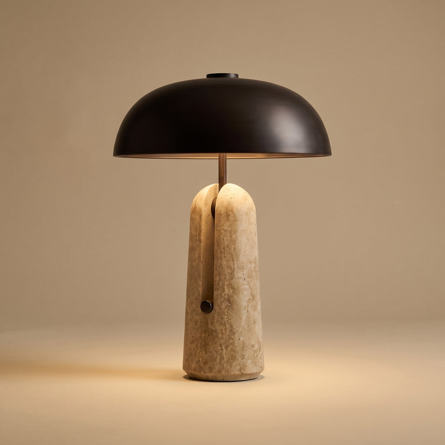 Sillon travertine and iron table lamp, lit, on a warm beige studio background