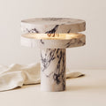 Strates marble table lamp, lit, on a warm off-white background