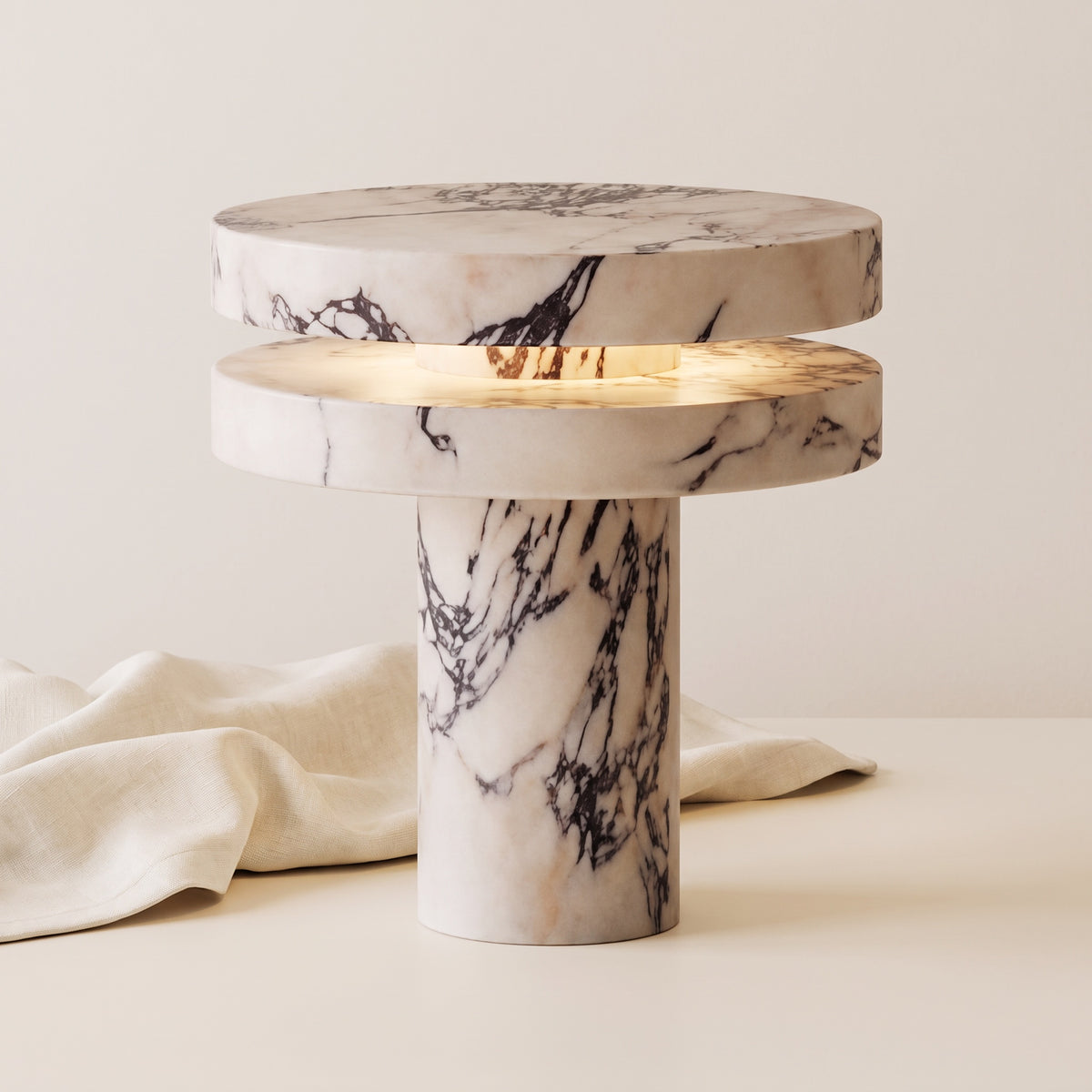 Strates marble table lamp, lit, on a warm off-white background