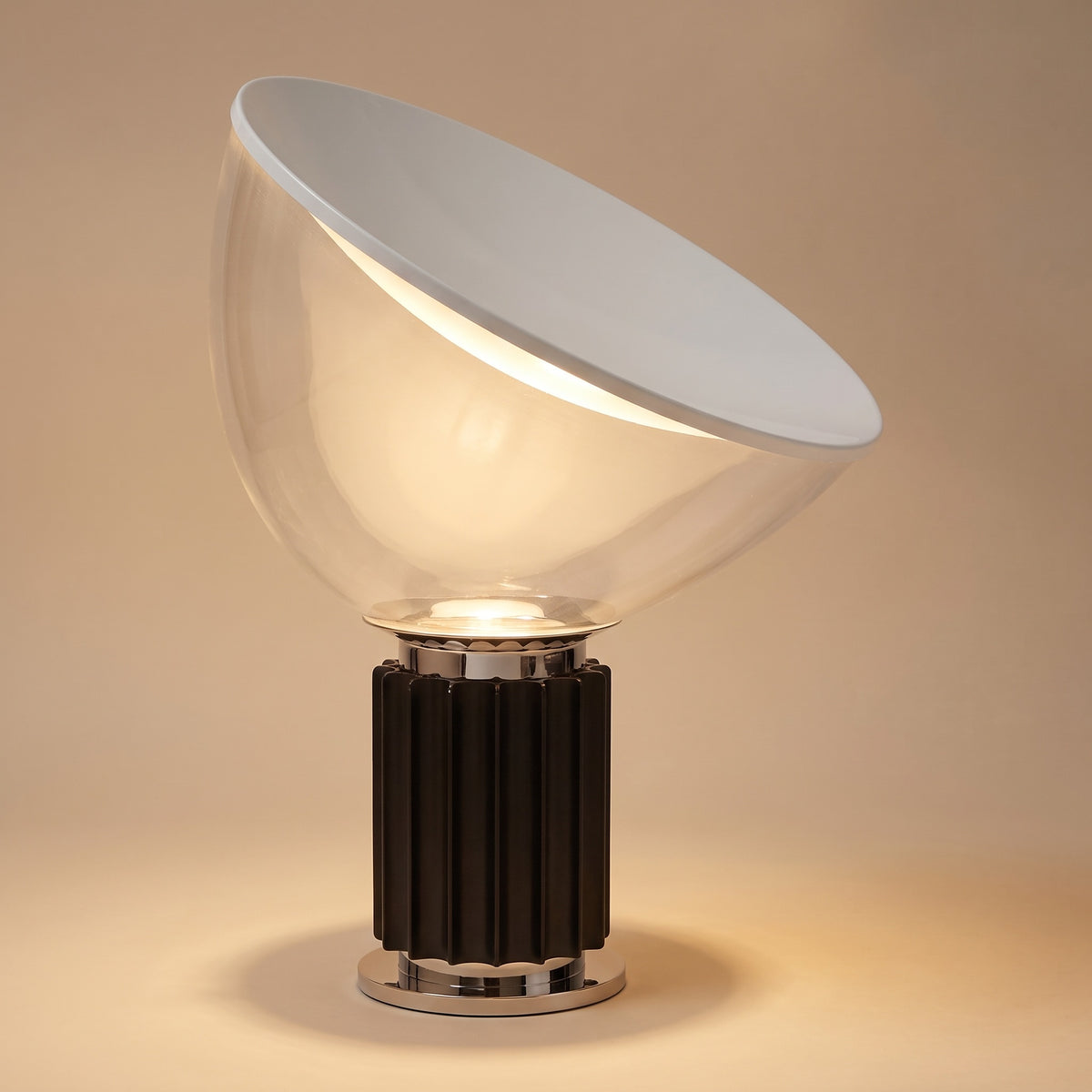 Zenith glass and metal table lamp, lit, on a warm beige studio backdrop